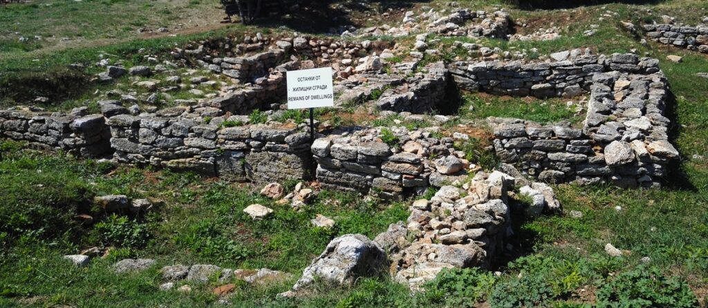 Picture of some ruins of a house or similar with a sign saying "Remains of Dwellings"