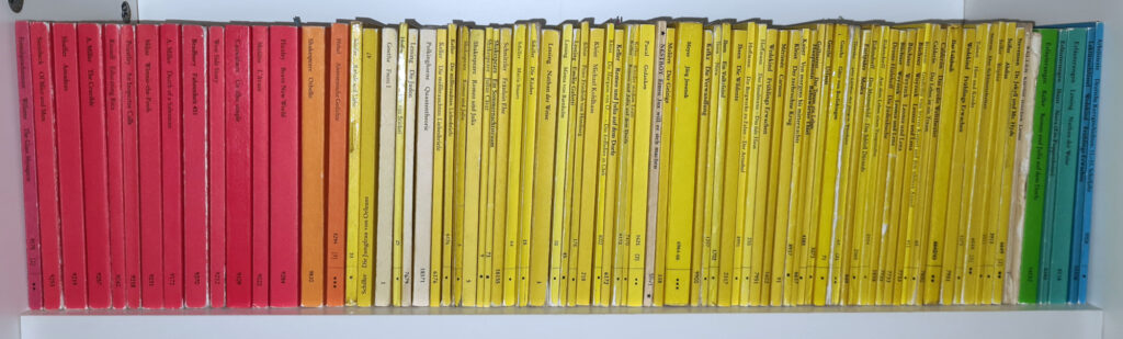 A shelf filled with Reclam books with red, yellow, green and blue small books